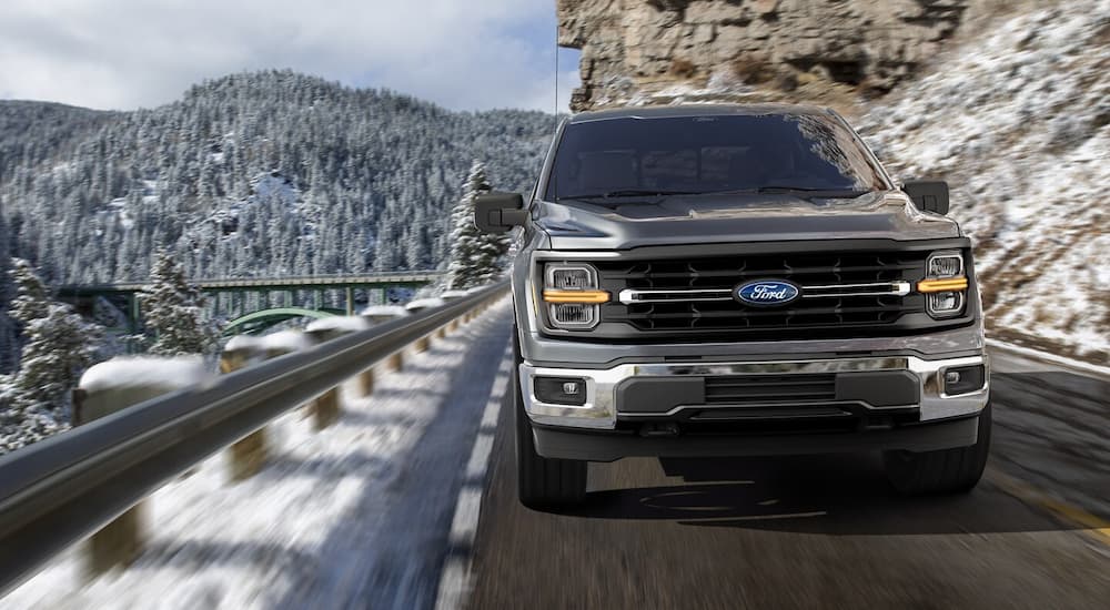 Grey 2025 Ford F-150 XLT driving on a mountain road.