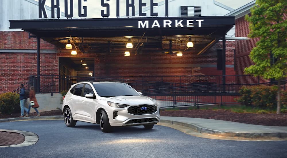 A white 2023 Ford Escape ST Line parked outside a market