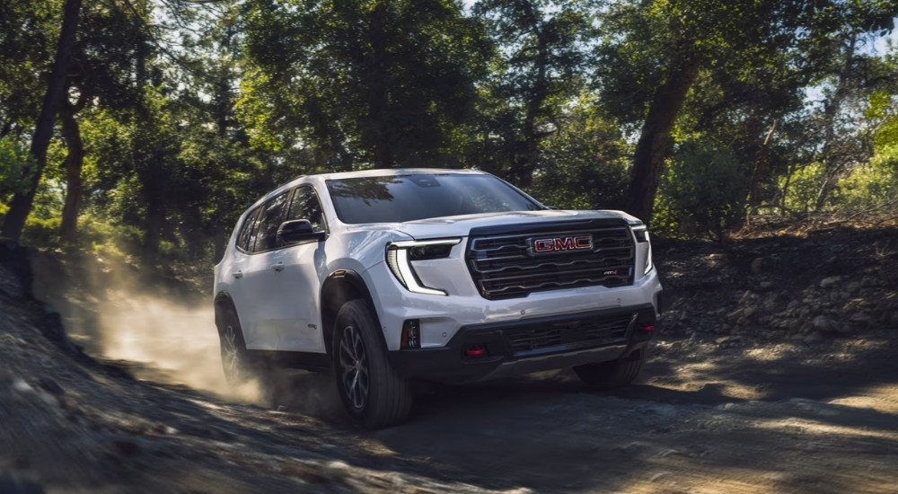 A white used 2024 GMC Acadia AT4 off-roading on a trail