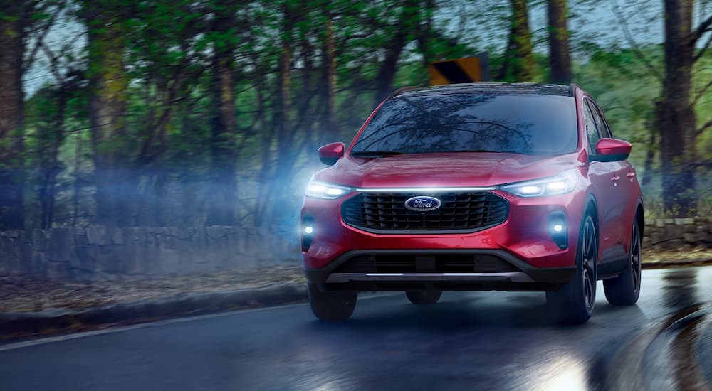 A red 2025 Ford Escape driving down a wet road from a Ford dealer near Menomonie