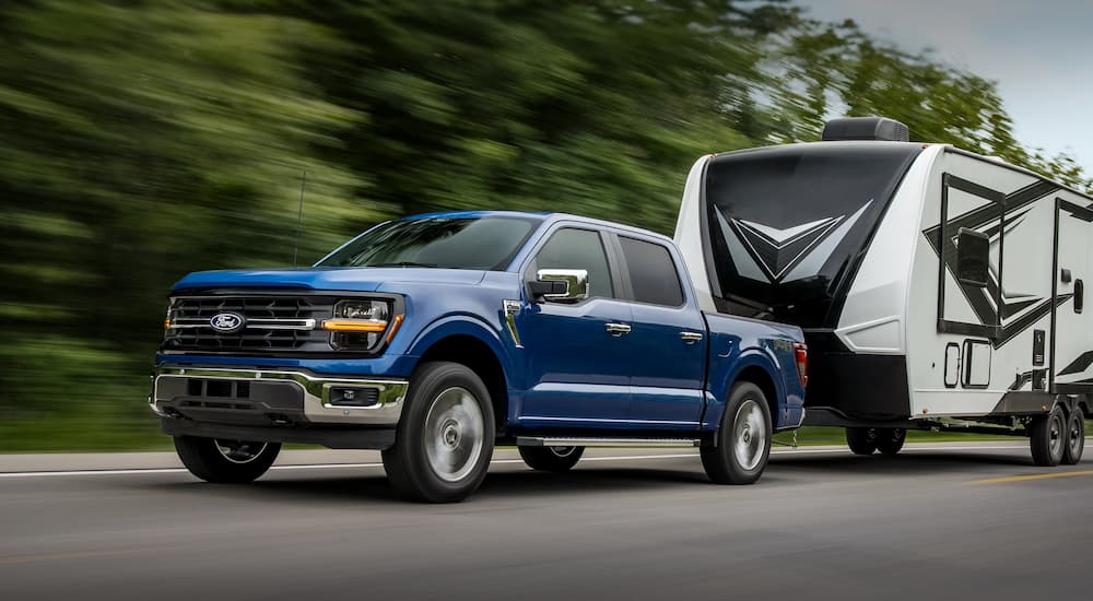 A blue 2026 Ford F-150 towing a camper