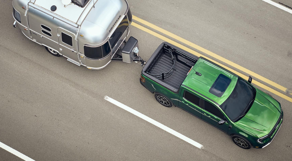 Green 2026 Ford Maverick XLT towing a camper