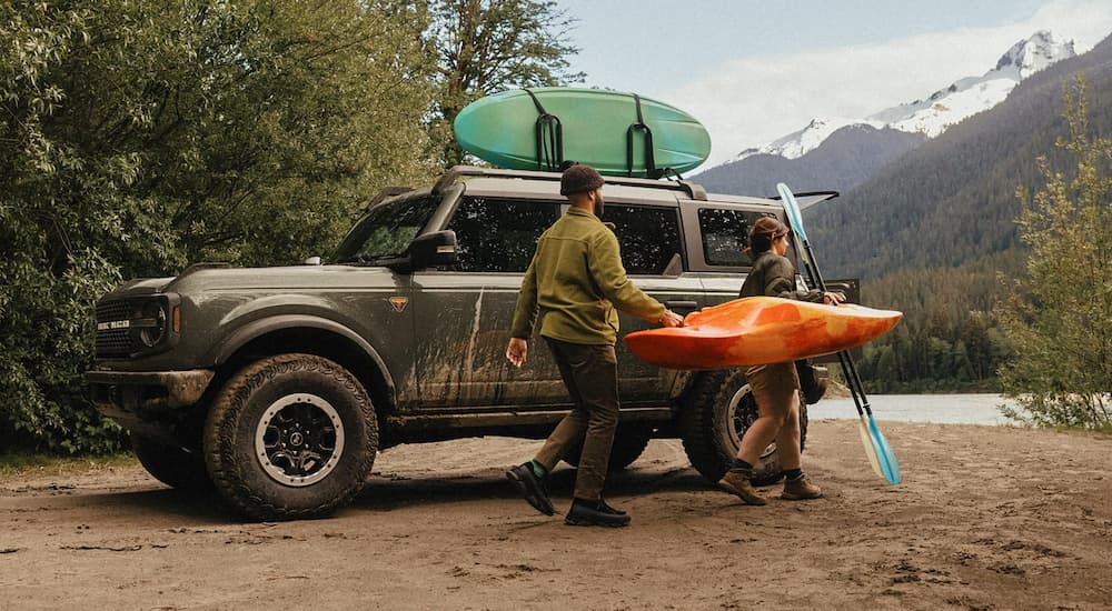 Two people carrying a kayak near a 2026 Ford Bronco