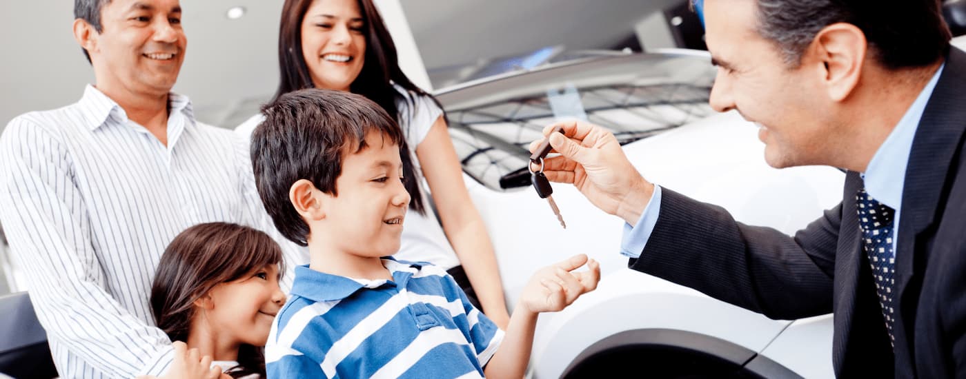 Car salesman giving a key to a family.