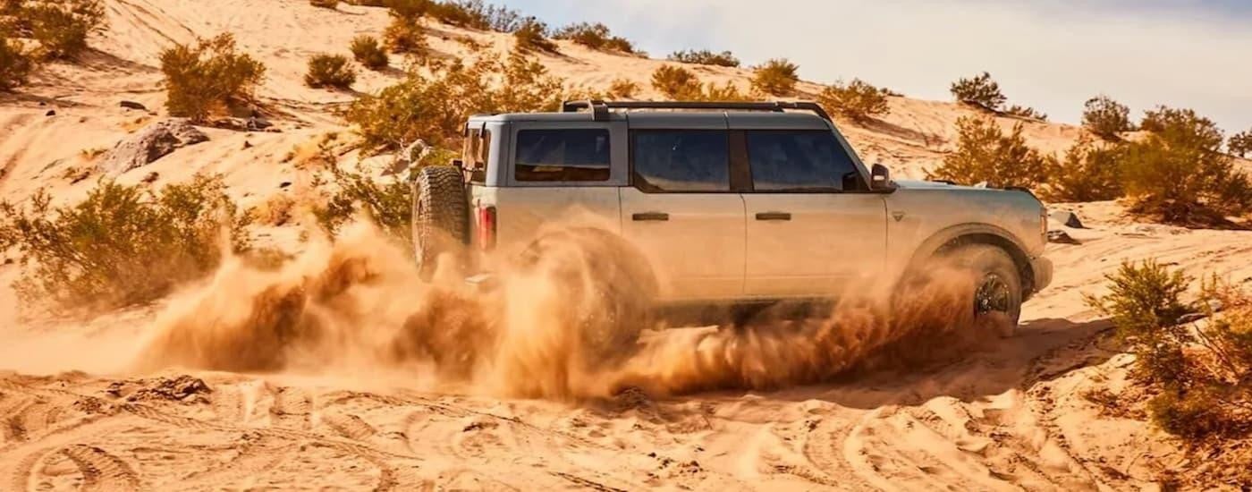 A silver 2021 Ford Bronco for sale is shown from the side while off-road.
